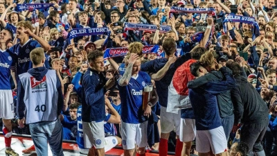 Die Spieler feierten mit den Anhängern, die nach dem Schlusspfiff auf das Spielfeld gestürmt waren. (Foto: Axel Heimken/dpa)