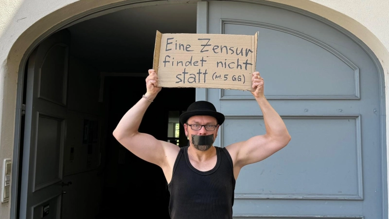 Mit einem Zitat aus dem Grundgesetz und zugeklebtem Mund stand Michael Jakob vorm Kulturzentrum am Ansbacher Karlsplatz. (Foto: Lara Hausleitner)