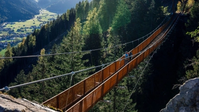 Wandern mit Aussicht: Die mehr als 100 Meter lange Hängebrücke im Stubaital führt an einem Berghang 46 Meter über den Boden und eröffnet einen Fernblick auf den Ort Neustift. (Foto: Nicolas Hafele/TVB Stubai Tirol/Nicolas Hafele/TVB Stubai Tirol/dpa)