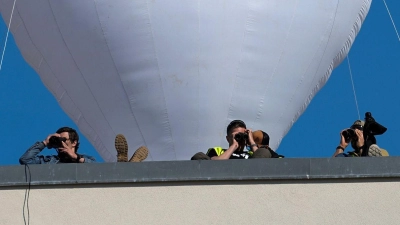 ESC-Fans haben ein großes Herz - aber es sind finstere Zeiten: Sicherheitsleute beobachten von einem Dach des Eurovision Village aus das erste Halbfinale des Eurovision Song Contest. (Foto: Martin Meissner/AP/dpa)