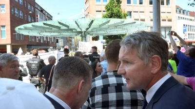 Björn Höcke steht am 25. Juni 2023 mit AfD-Sympathisanten vor Gegendemonstranten nahe einer Gedenkstele. (Foto: Karl-Josef Hildenbrand/dpa)